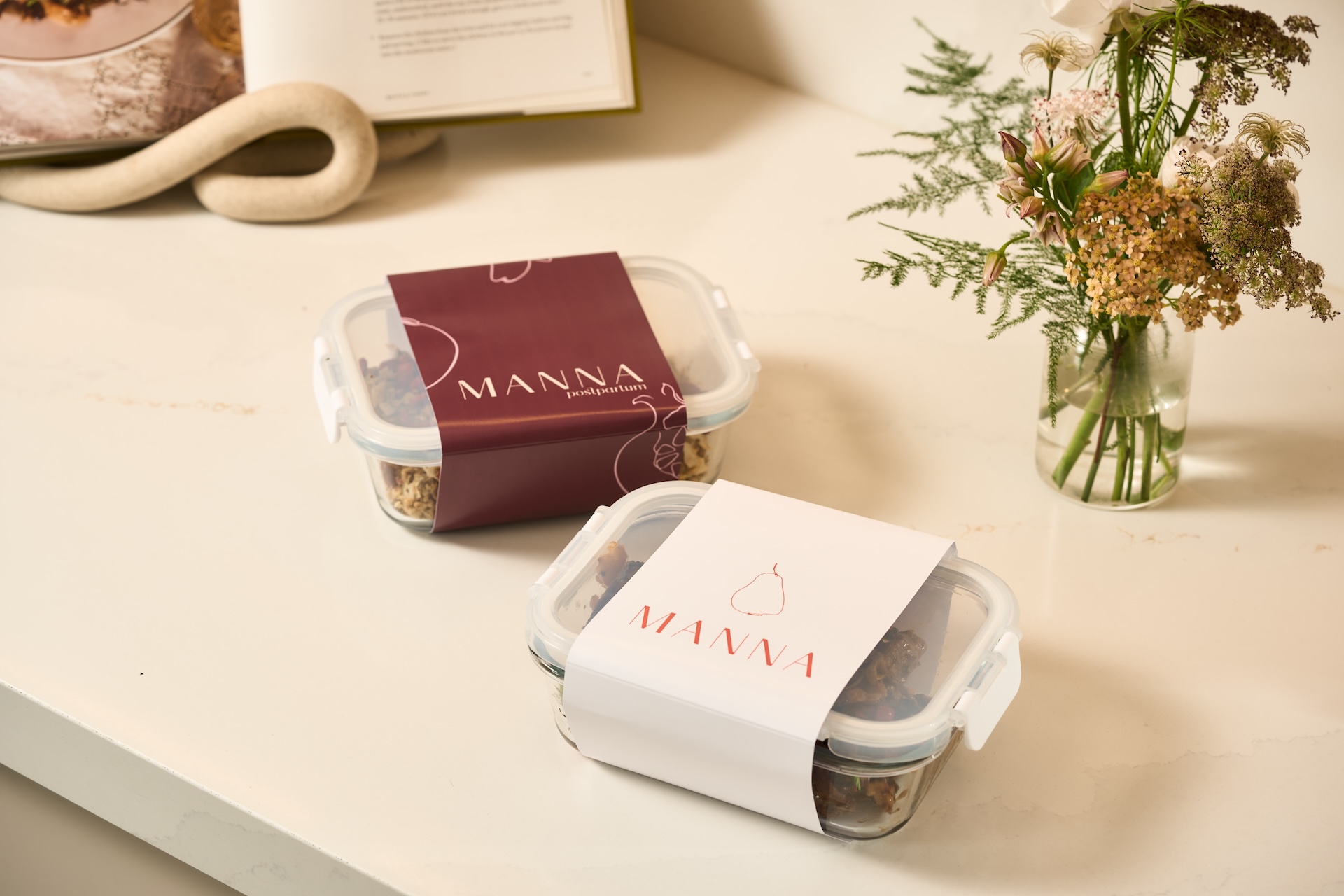 Manna glass containers with branded sleeves on a kitchen counter